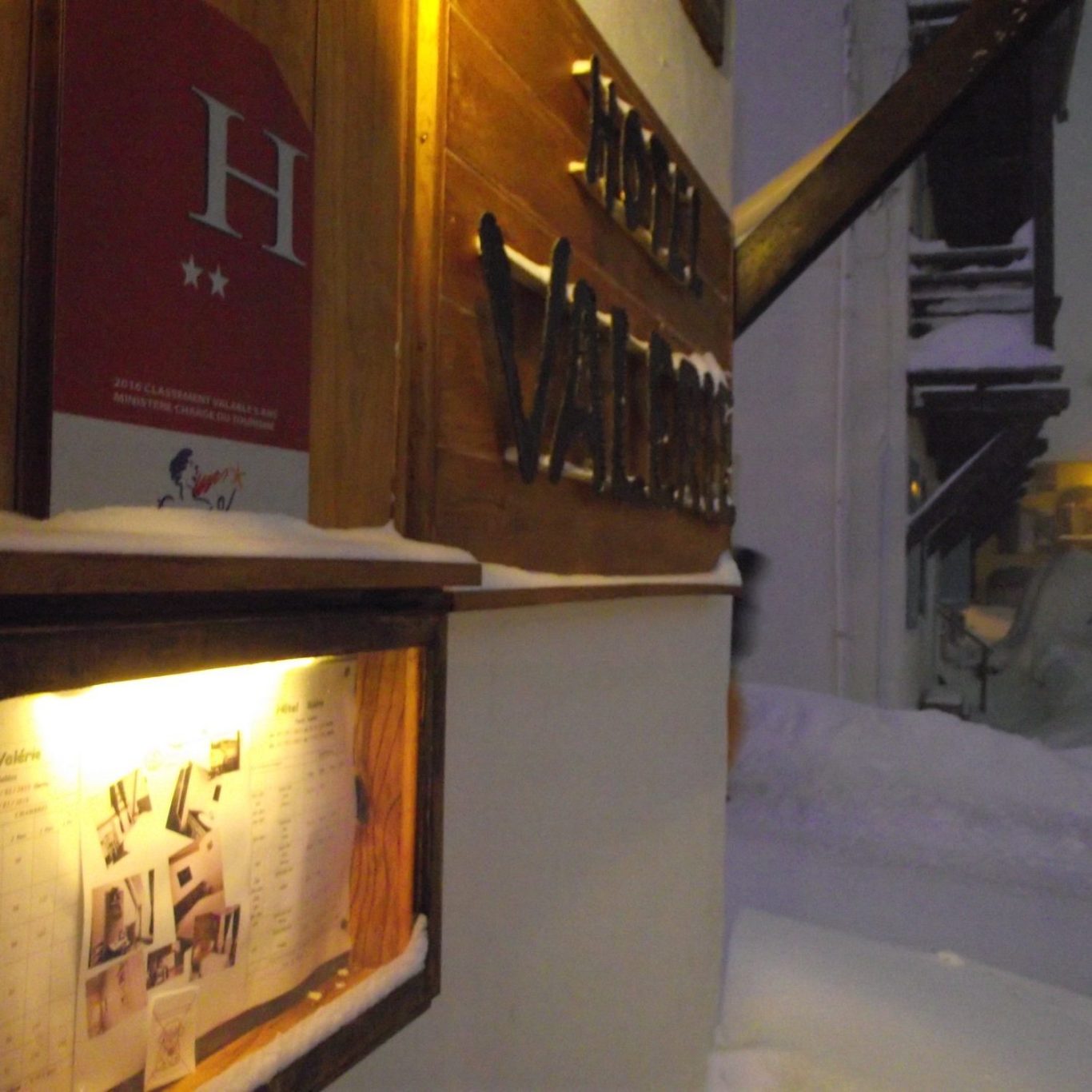 LOGO entrée hôtel Panneau en bois avec le nom "Hôtel Vallée" illuminé, neige au sol.